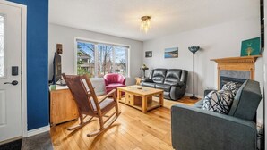 A living room with a rocking chair, a gray sofa, a wooden coffee table, and a fireplace.