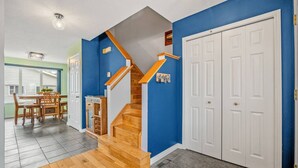 A staircase with wooden steps and a handrail, leading to a room with a white door and a blue wall.