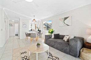 Un salon moderne avec un canapé gris, une table basse ronde et un coin repas comprenant des chaises et une table.