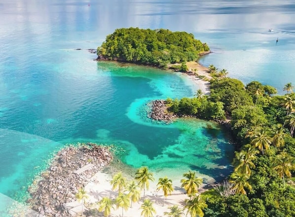 A tropical island with clear turquoise waters, lush greenery, and a small rocky beach area. - Studio Ti'Tourel - T2 terrace 4 pers, 3mn from Anse Mitan beach (Les Trois-Îlets)