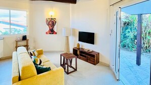 Uma sala de estar com sofá, televisão, abajur e janela.