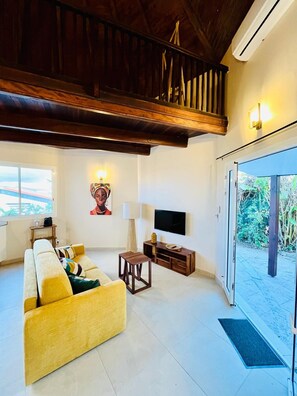 A living room with a sofa, a TV, a lamp, and a window. - Studio Ti'Tourel - T2 terrace 4 pers, 3mn from Anse Mitan beach (Les Trois-Îlets)
