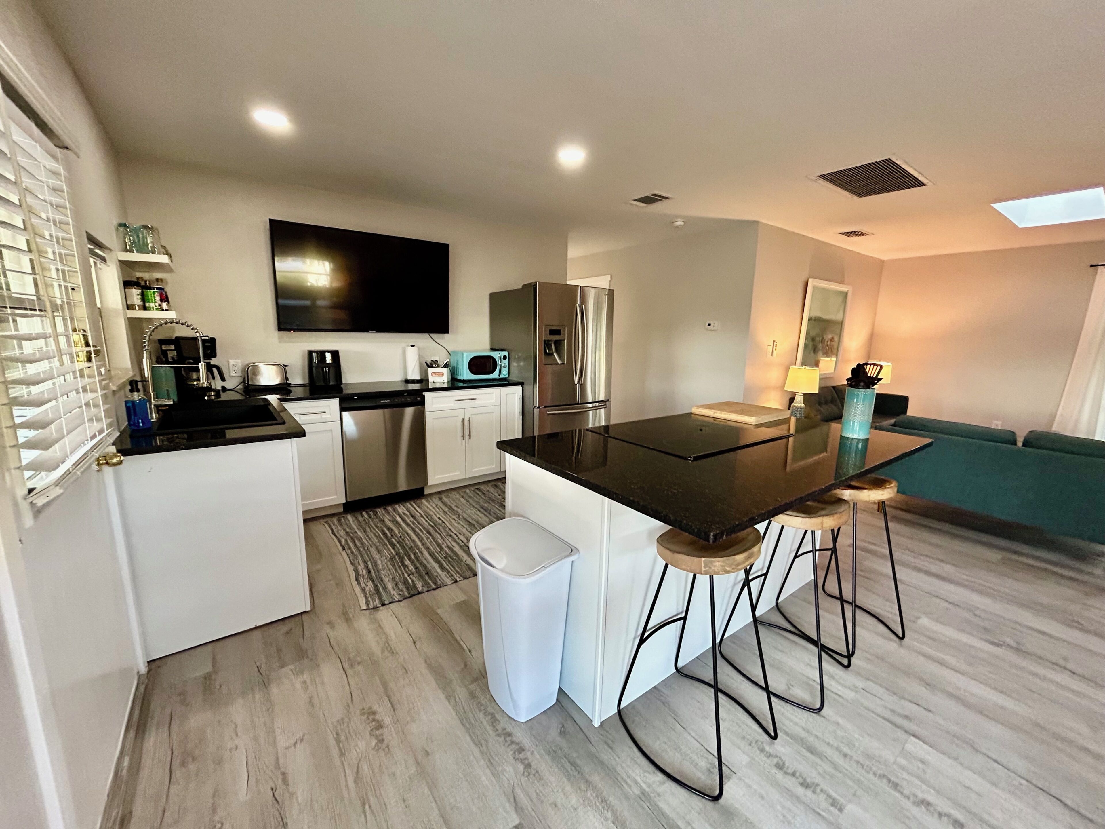 A modern kitchen with a central island, stainless steel appliances, and a flat-screen TV.
