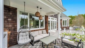 An outdoor patio with a hanging chair, a sofa, and a table. - Exquisite Shinnecock Hills Classic, Private Yard featuring Heated Pool,... (Southampton)