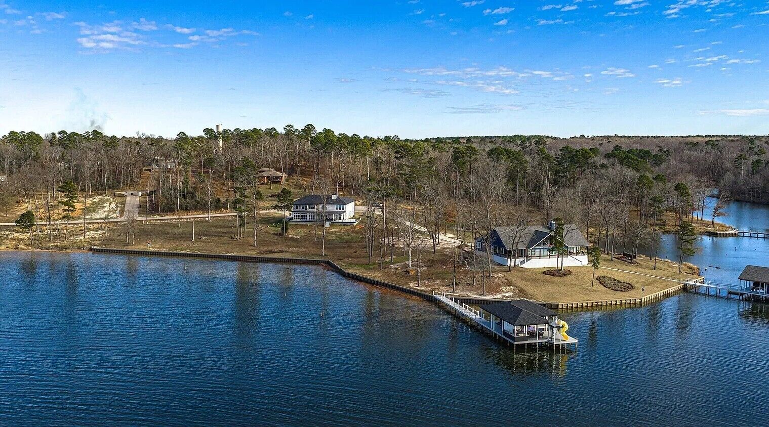 Une propriété au bord du lac, comprenant un quai, une maison et un bateau.