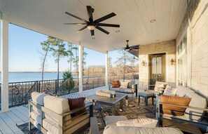 A covered outdoor seating area with a view of the water, furnished with sofas and tables. - Lakefront Estate Sleeps 18, Bunk & Game Room & Boat House w/Swim Hole & Kitchen! (Pittsburg)