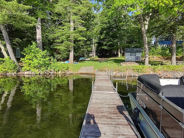 A wooden dock extending into a calm body of water, surrounded by lush greenery and trees.