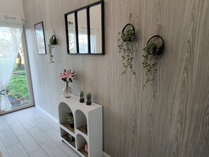 A room with a white console table, a mirror, and hanging planters against a wooden wall. - House with pool marias poitevin (Saint-Sigismond)