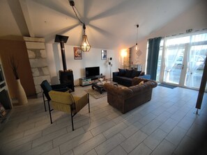 A living room with a fireplace, sofa, TV, and a large window with curtains. - House with pool marias poitevin (Saint-Sigismond)