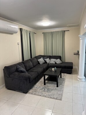 Ein Wohnzimmer mit einem dunkelgrauen Sofa, einem Couchtisch und einem hellen Teppich.