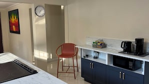 A modern kitchen with a marble countertop, a built-in microwave, and a coffee maker. - Stay Exchange Modern Chill Retreat w/ Private Backyard Oasis (Ocho Rios)