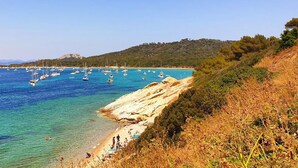 A coastal landscape with clear blue waters, rocky shorelines, and a hilly backdrop. - Beachside Family Holiday Home (Hyères)