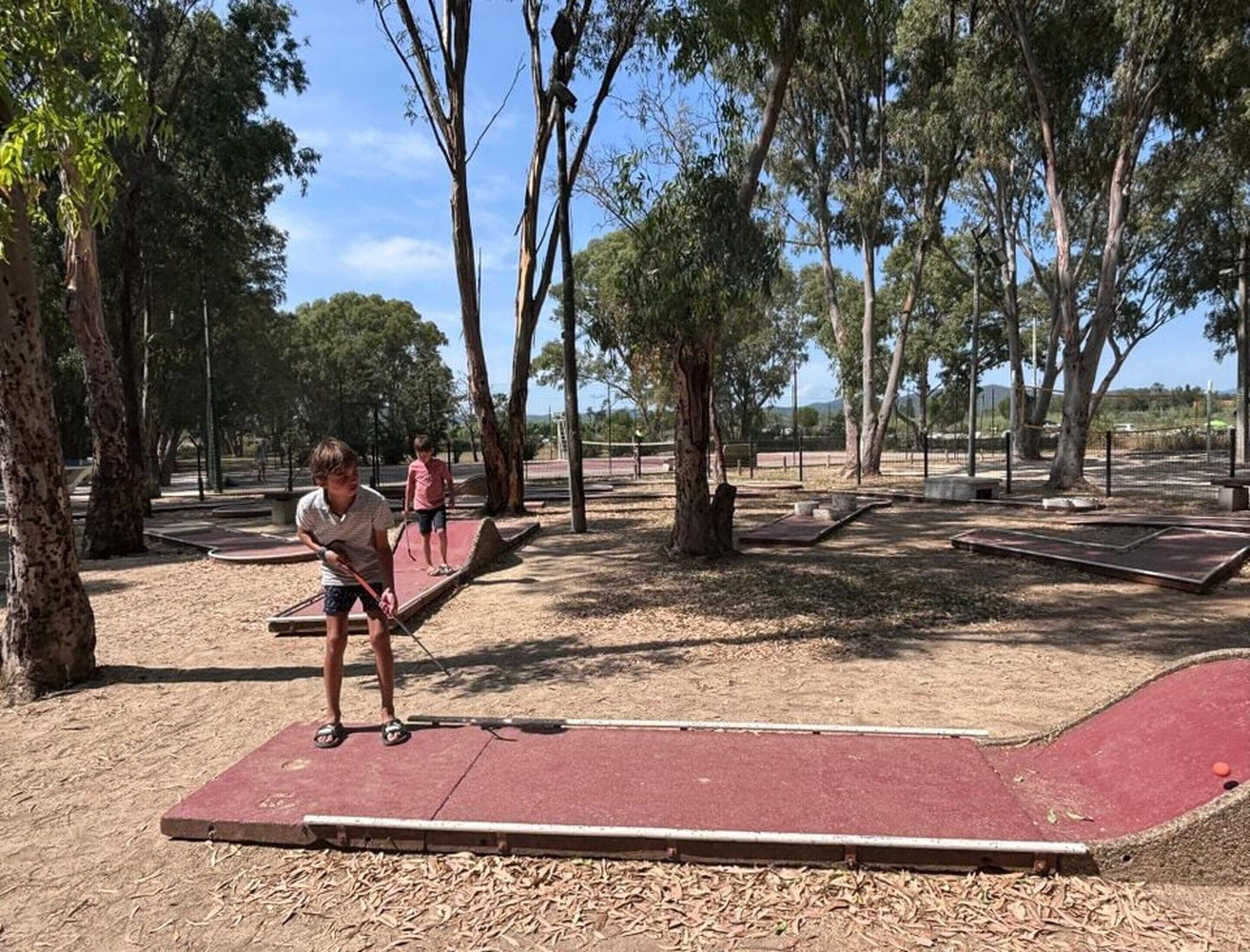 Un parc avec une aire de jeux rouge, des arbres et un ciel dégagé.