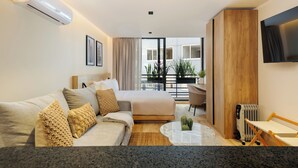 Habitación de hotel con cama, sofá, una mesita, televisión y vistas al exterior.