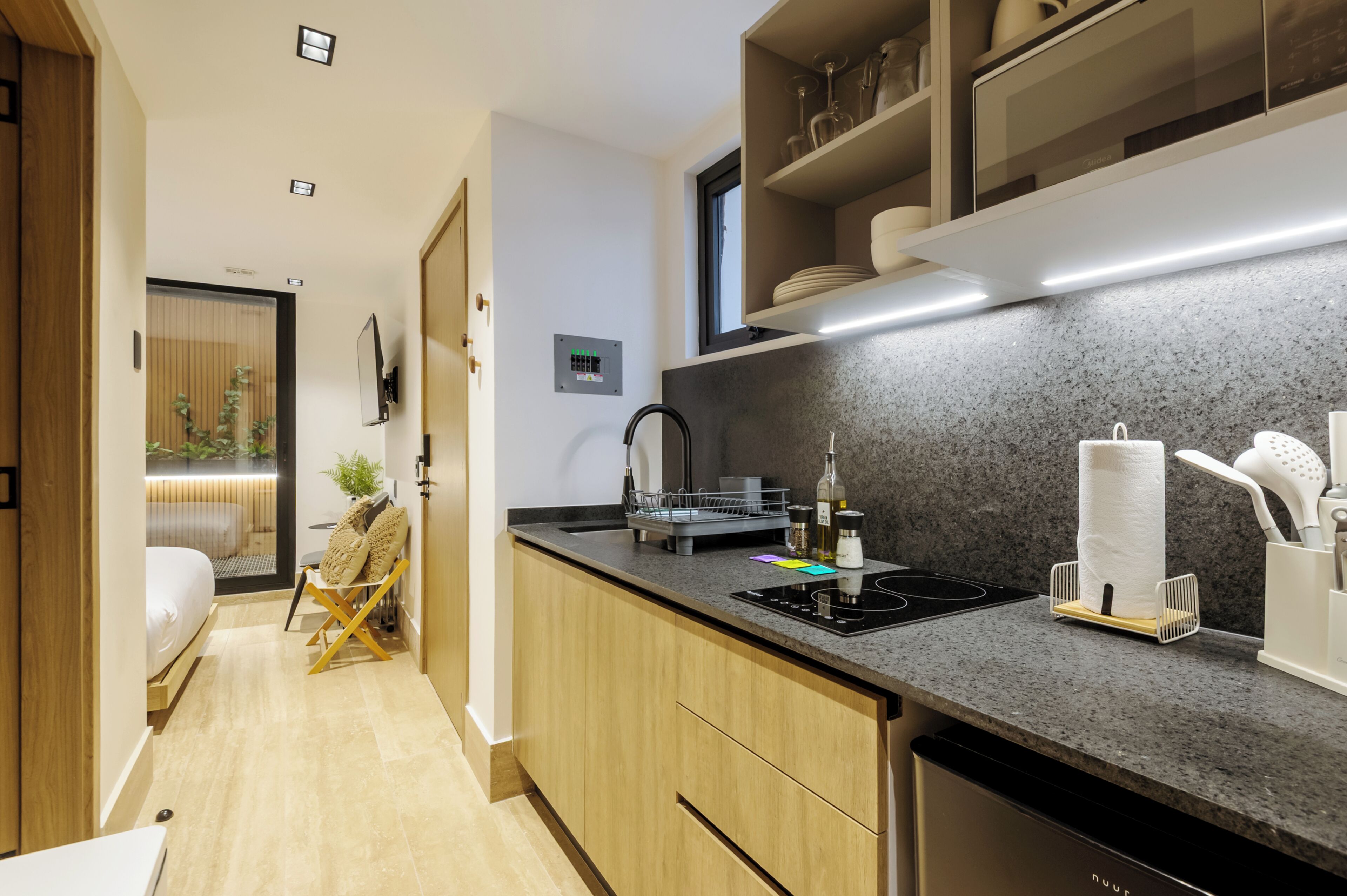 Cocina moderna con mostrador, pileta y estufa.  Hay una zona de comedor con una silla y una mesita.