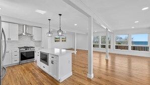 A spacious kitchen with white cabinetry, a stainless steel range, and a wooden floor. - Baiting Hollow Waterfront, Private Beach & Stunning Sunsets (Riverhead)
