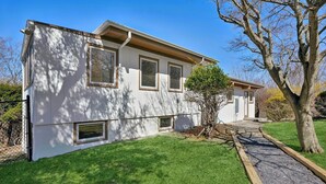 A two-story house with a front yard, a tree, and a pathway leading to the entrance. - Baiting Hollow Waterfront, Private Beach & Stunning Sunsets (Riverhead)
