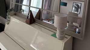 A piano with a large mirror above it, a lamp, and a plant on the piano. - Guildford Apartment with Free Parking & Garden (Guildford)