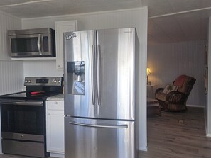 A kitchen with a stainless steel refrigerator, a microwave, an oven, and a water dispenser. - Perfect 2-bedroom house with community pool near beaches in Fort Myers (Fort Myers)