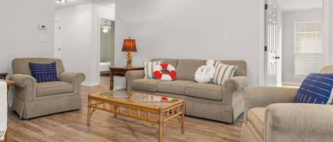 A living room with a sofa, two armchairs, a coffee table, and a lamp.