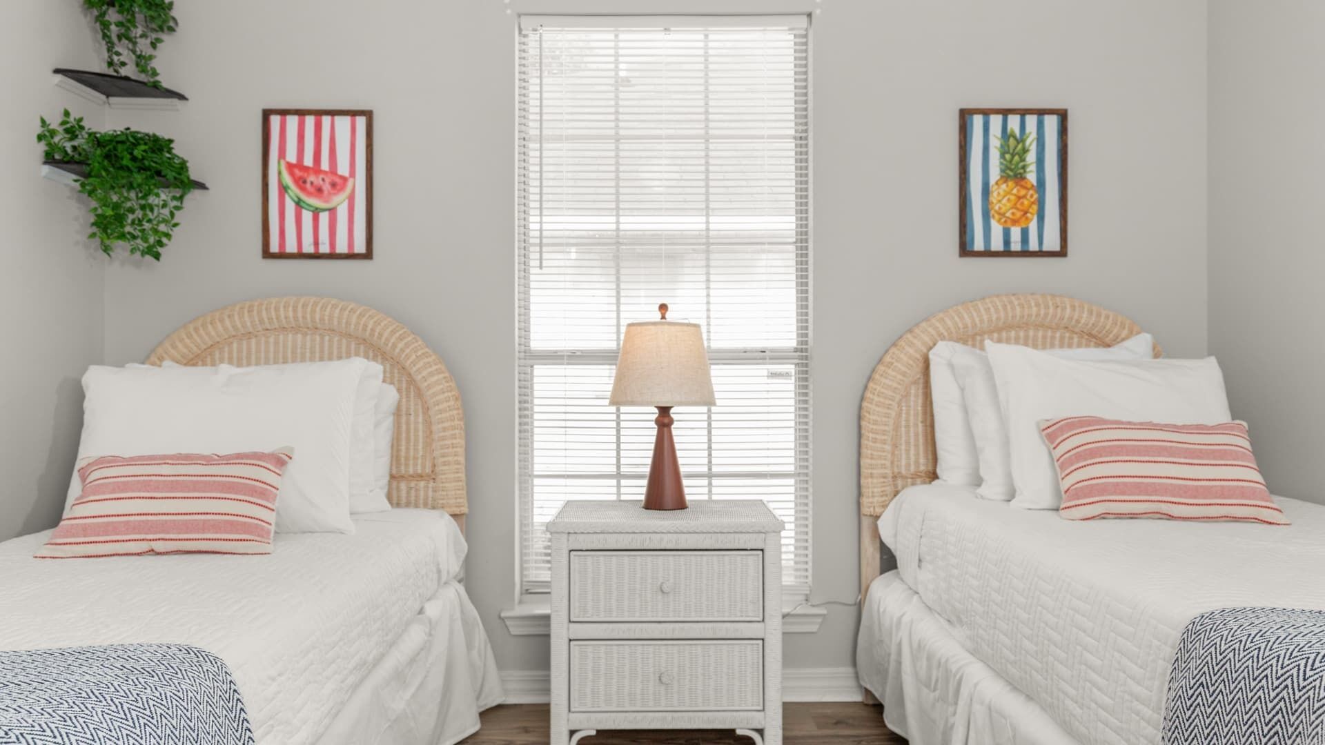 A bedroom with two beds, a nightstand with a lamp, and two framed pictures on the wall.