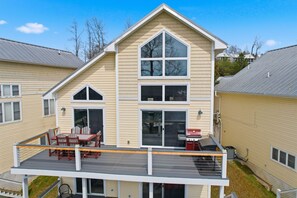 Ein zweistöckiges Haus mit Terrasse, großen Fenstern und Grill.