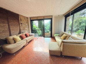 A spacious living area with two sofas, a stone wall, and large sliding glass doors leading to a garden.