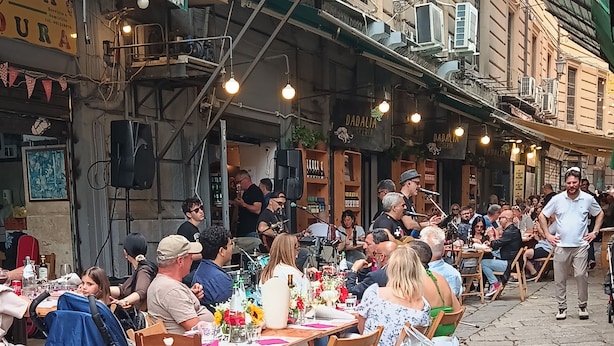 Un espacio exterior para comer con mesas y sillas, rodeado de edificios.