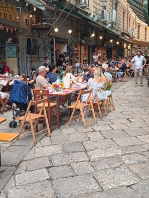 Een terras met tafels en stoelen, omgeven door gebouwen.