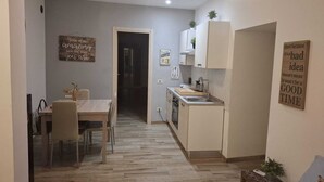 Un espacio habitable compacto con comedor, kitchenette y un pasillo que conduce a otra habitación.