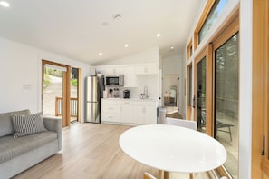 A modern kitchen with white cabinets, a stainless steel refrigerator, and a microwave. - Northstar Ranch Modern Cabin by Beaver Lakes (Whitefish)