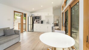 A modern kitchen with white cabinets, a stainless steel refrigerator, and a microwave. - North Star Ranch Modern Cabin by Beaver Lakes (Whitefish)