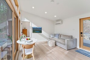 A modern living room with a dining area, a sofa, and a television. - North Star Ranch Modern Cabin by Beaver Lakes (Whitefish)