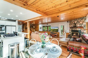 A spacious log cabin interior with a dining area, kitchen, living room, and fireplace. - The Chalet at North Star Ranch - Secluded 40 Acres (Whitefish)