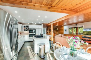 A modern kitchen with white cabinets, a stainless steel refrigerator, and a dining area with a table set for two.