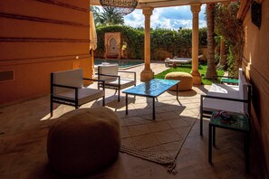 A covered outdoor seating area with a pool, chairs, and a table. - Golf villa amelkis 4 bedrooms (Marrakech)