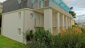 A two-story building with a balcony, a circular window on the side, and a staircase leading to the upper floor. - Family Escape Near Trescadec (Audierne)