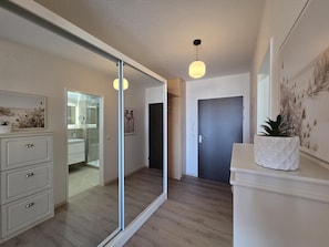 A modern interior with a sliding glass door leading to a bathroom, a white dresser, and a potted plant.