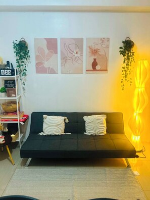 Ein modernes Wohnzimmer mit einer Couch, Wandbildern und einer außergewöhnlichen, gelben Leuchte.