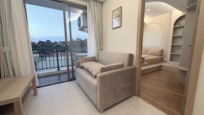 Ein modernes Wohnzimmer mit einer Couch, einem kleinen Tisch und einem Balkon mit Geländer.
