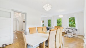 A bright dining area with wicker chairs, a white table, and a foosball table.