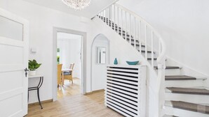 A staircase with white railings, a white radiator, and a door leading to a room with a plant.