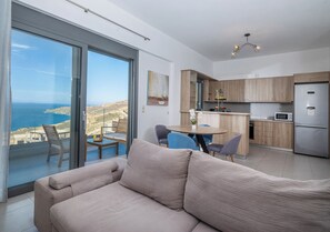 Un apartament modern amb un balcó, un sofà, zona de menjador i cuina.