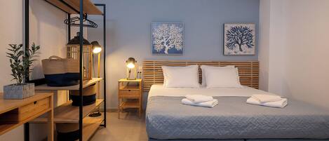A neatly arranged bedroom with a bed, bedside tables, a desk, and a shelf unit.