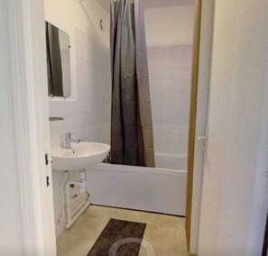 A bathroom with a white sink, a mirror, a shower curtain, and a bathtub. - Private Room in a Shared Flat - Lyon 8 (Lyon)