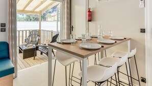 A dining area with a table set for four, a fire extinguisher, an air conditioning unit, and a view through a glass door to an outdoor patio. - Adriatic Family Retreat With Terrace (Brtonigla)