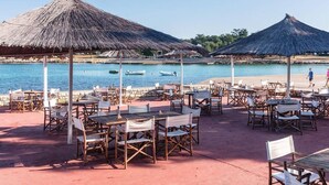 A beachside restaurant with thatched umbrellas, wooden tables, and chairs. - Adriatic Family Retreat With Terrace (Brtonigla)