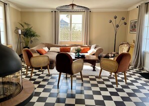 Un salon avec un sol à carreaux, un canapé, deux fauteuils, une table basse et un lampadaire.