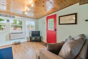 A living room with a red door, a television, and a couch.