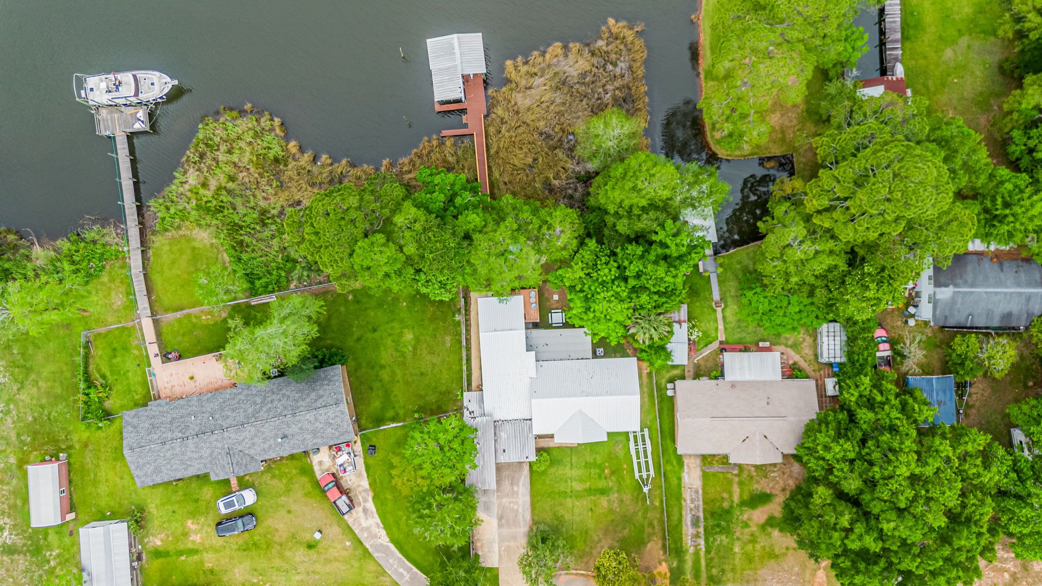 An aerial view of a residential area with houses, a dock, and a small body of water.